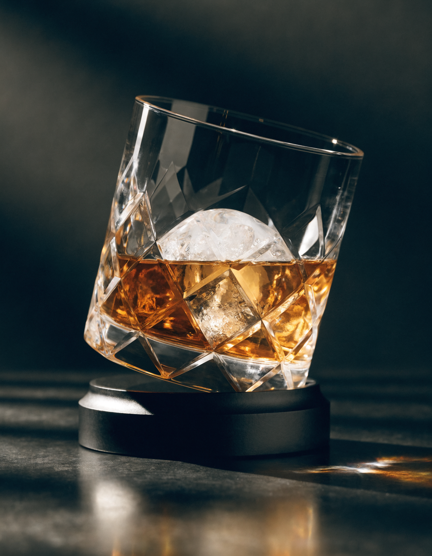 The Oember Vortex gemstone-cut rotating whiskey glass with amber whiskey and ice, dark luxury product shot
